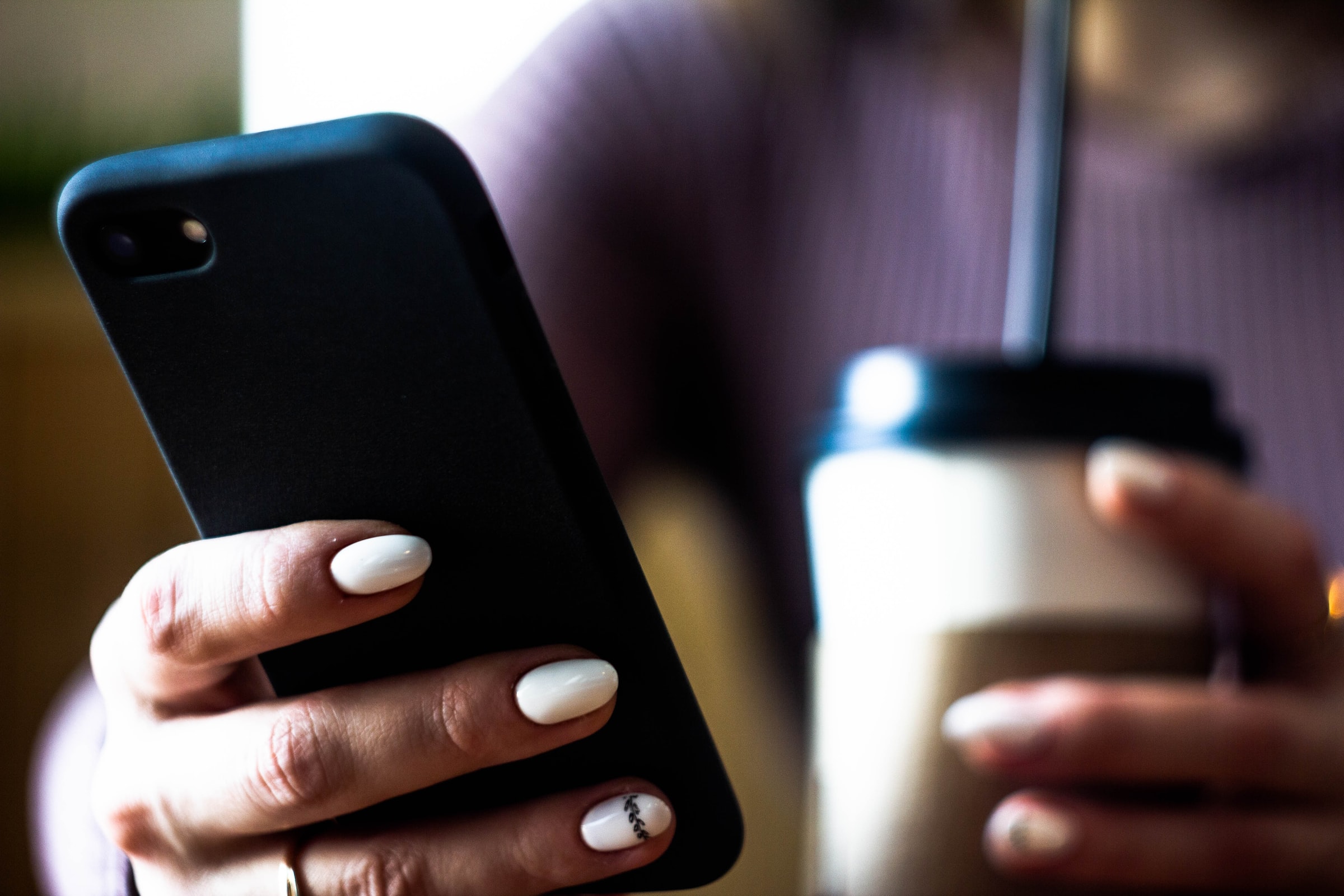 Someone on a phone with a drink - Photo by Vladimir Mun on Unsplash