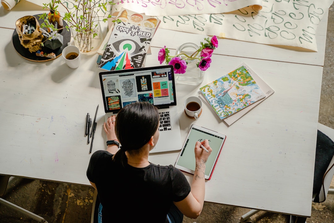Woman infront a table with art material and computer. Photo by Antoni Shkraba - Pexels