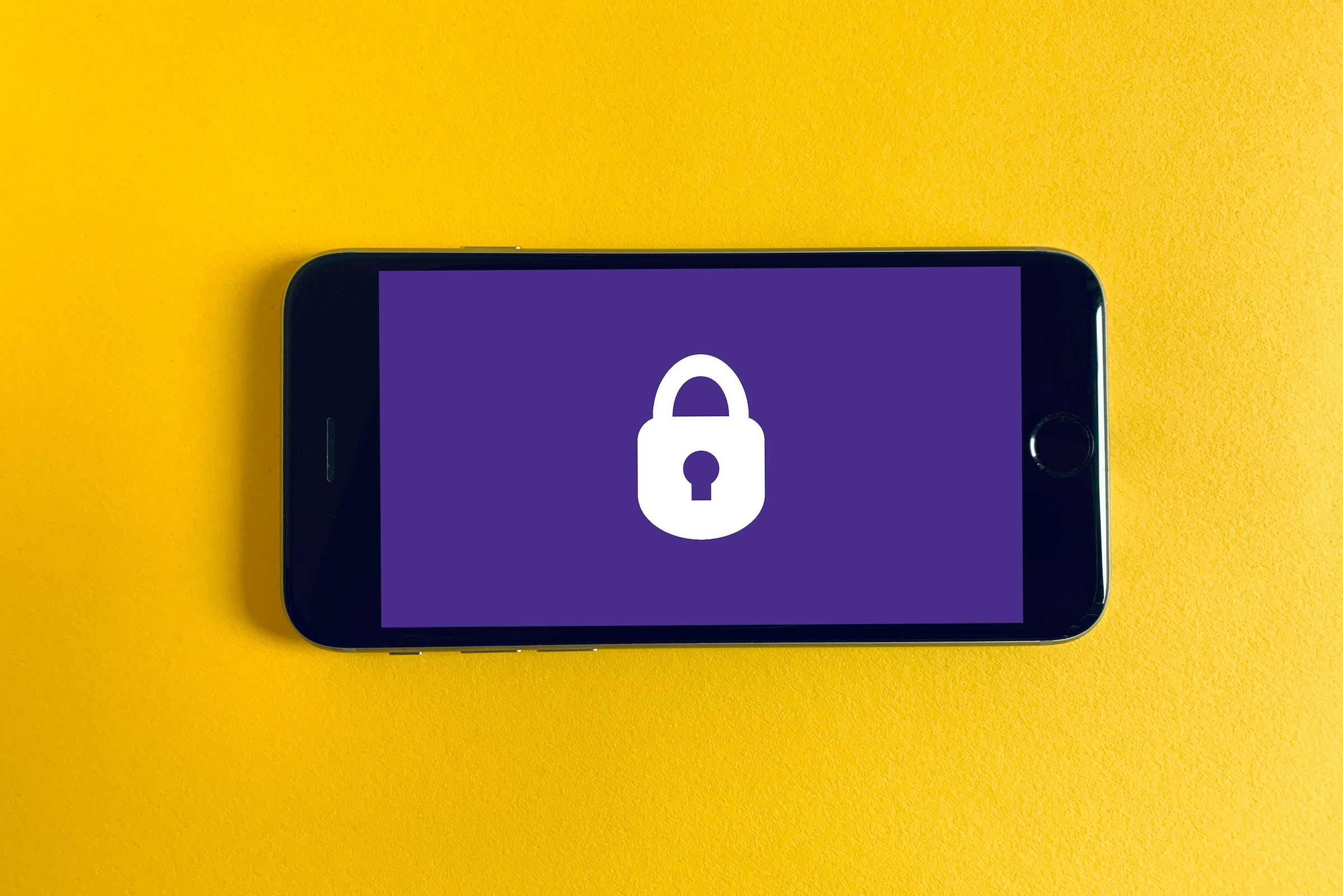 Black iphone on yellow background with a padlock. Photo by Franck on Unsplash